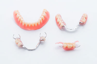 The image displays a set of dentures with visible teeth and gum-like structures, presented on a white background, possibly for promotional or illustrative purposes.