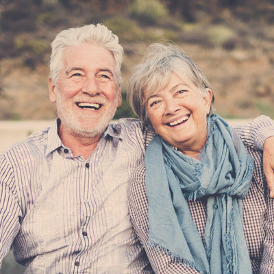The woman in the image is smiling at the camera while leaning on a wooden surface.