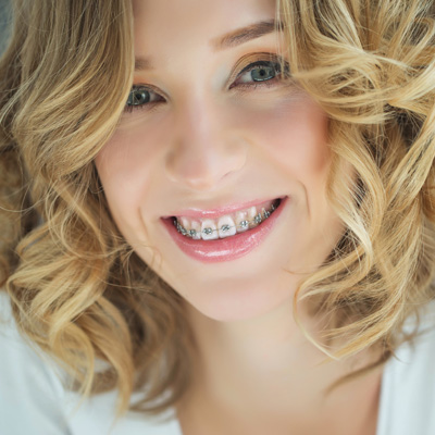 A woman with straight teeth and braces smiling at the camera.