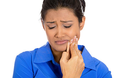 The image features a woman with her eyes closed, holding her face in pain or distress, possibly indicating discomfort or sadness.