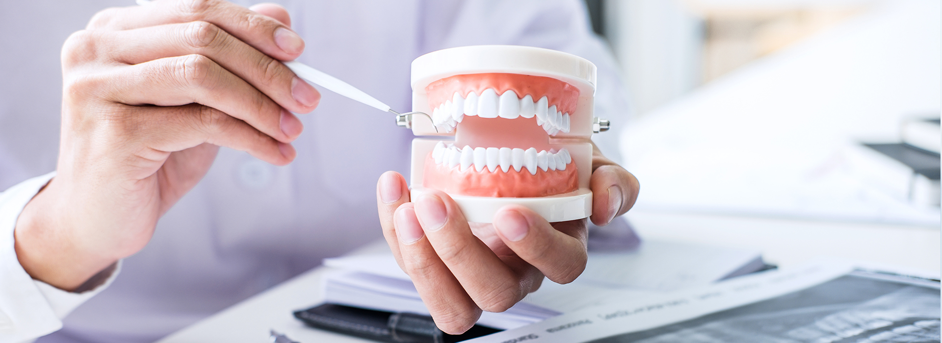 The image shows a person holding a toothbrush near a cup with a toothpaste tube, demonstrating dental hygiene practices.