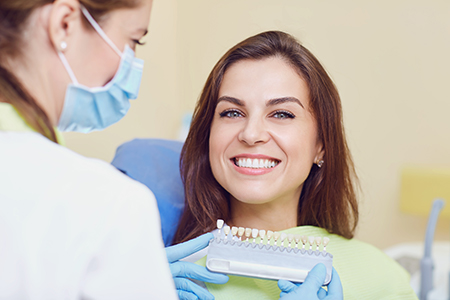 A dental hygienist assisting a patient with teeth cleaning equipment.