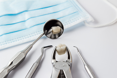 The image shows a collection of dental tools, including a toothbrush with toothpaste applied, placed on a blue cloth, which is likely a sterilization wrap, suggesting a dental care setting.