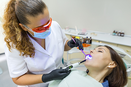 A dental hygienist assisting a woman during a teeth cleaning procedure.