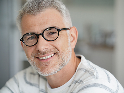 The image features a man with glasses smiling at the camera.